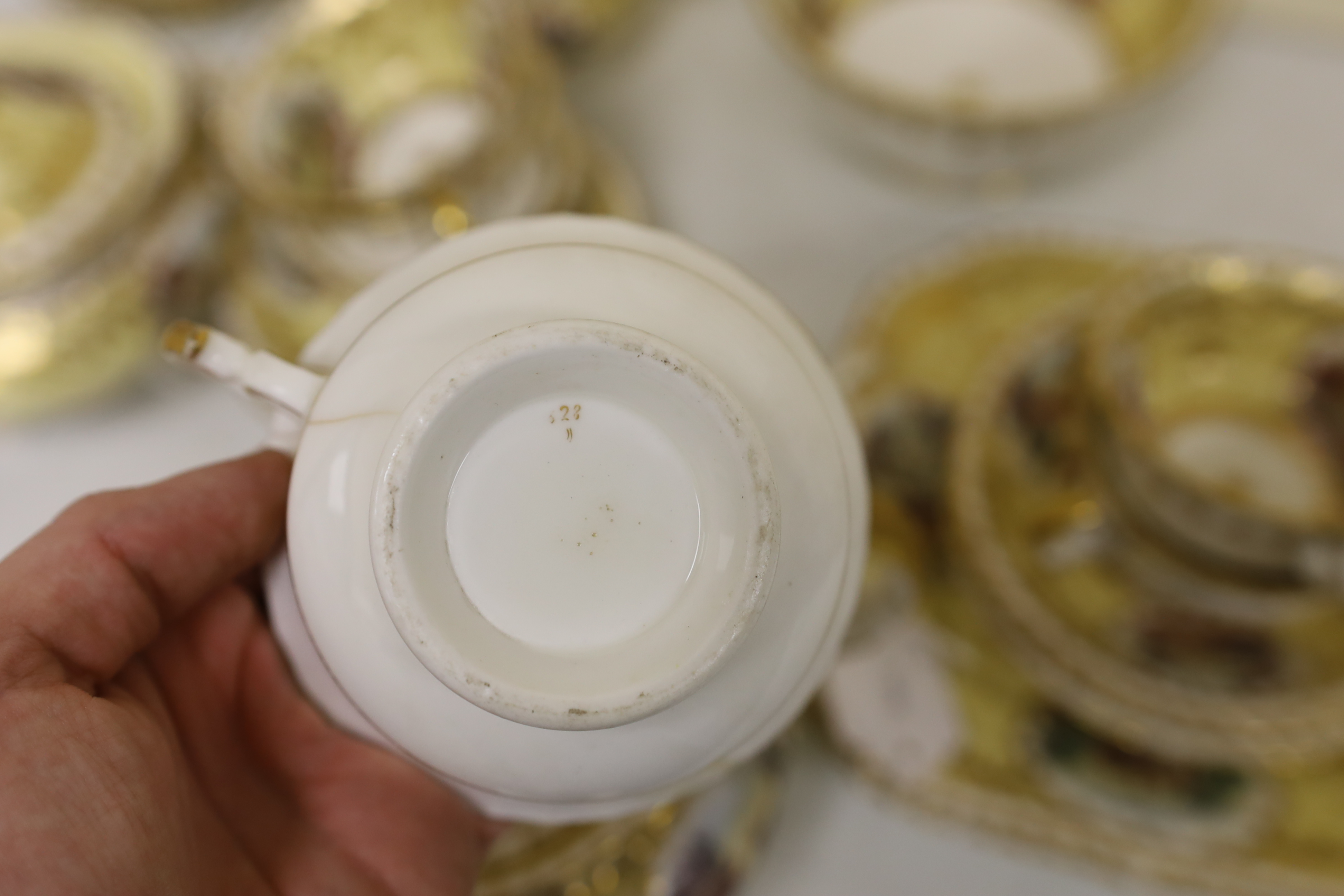 An English porcelain tea set, c.1835-45, including a teapot and cover, sucrier and cover, slops bowl, milk jug, teacups and saucers, two cake plates, each piece painted with buildings in landscapes, yellow ground, patter